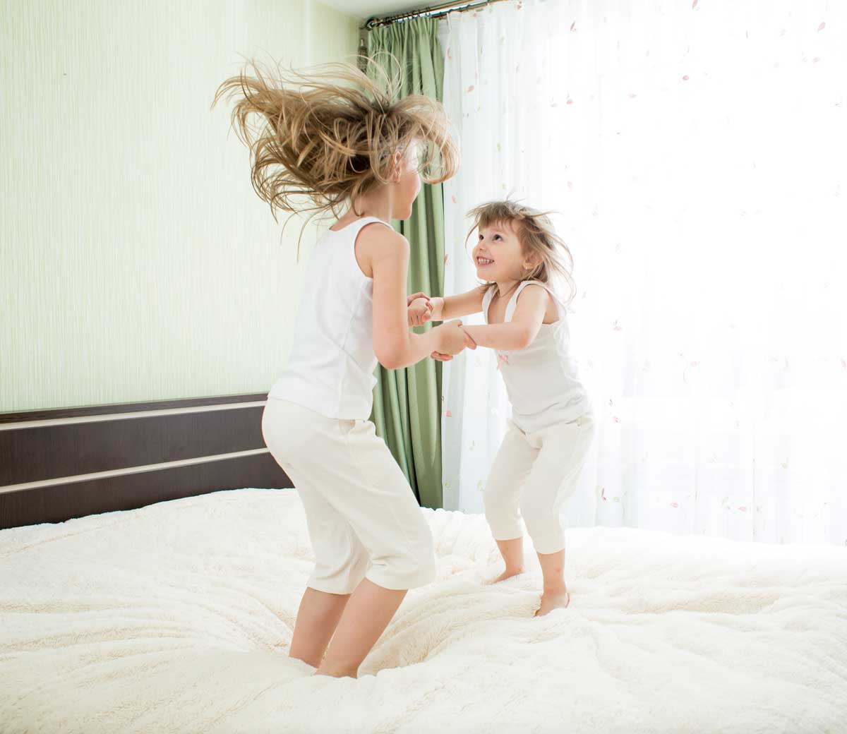 Girls jumping on bed